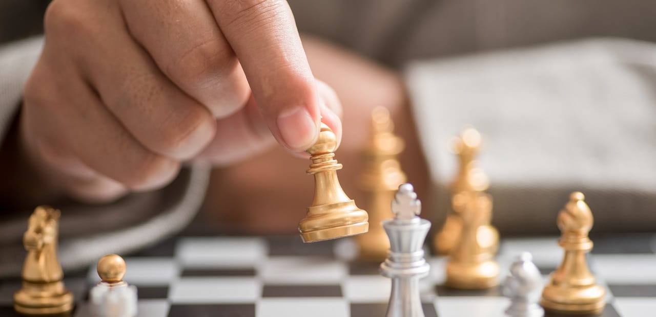 Hand moving chess piece on chess board. 