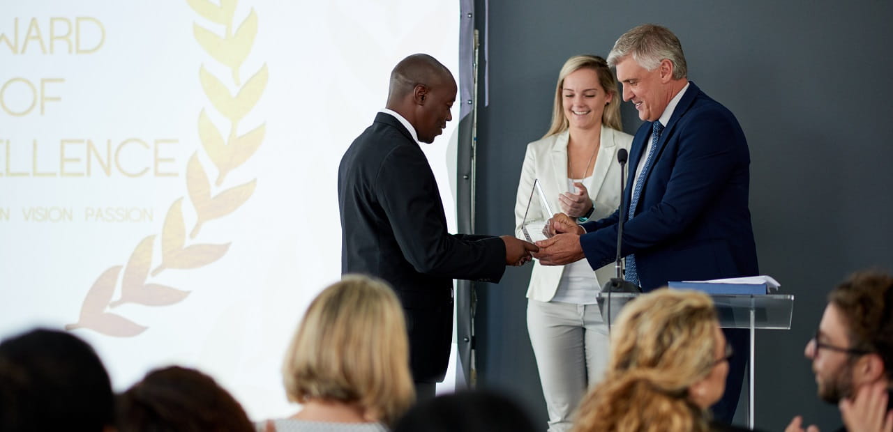 Man accepts an award onstage at a ceremony in front of a crowd.