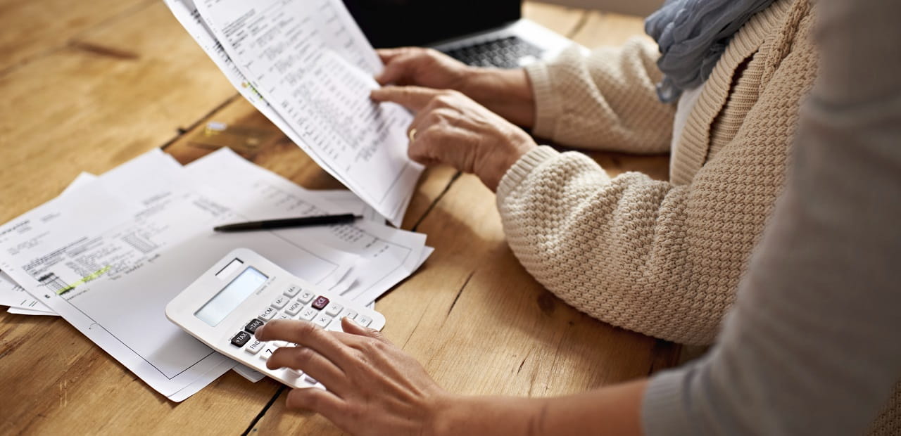 Retirement age woman points to a printed form at a table. 