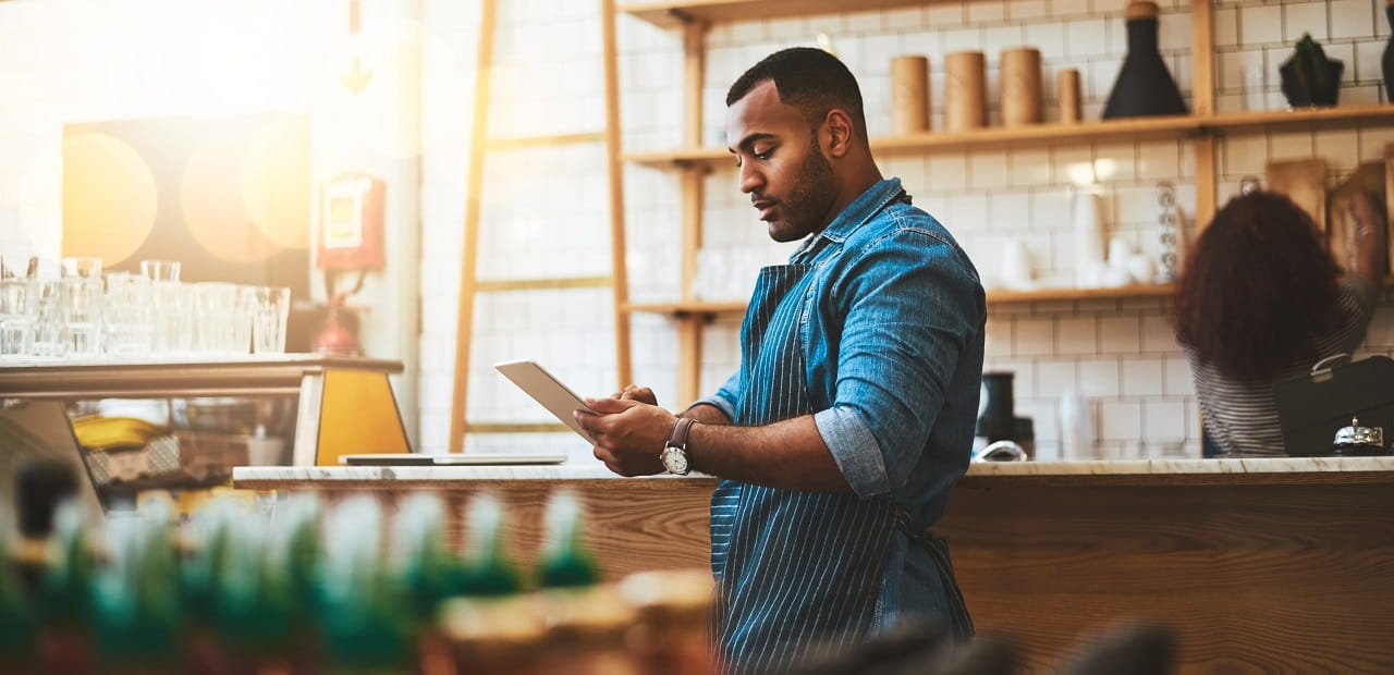 Man stands in his business using an iPad