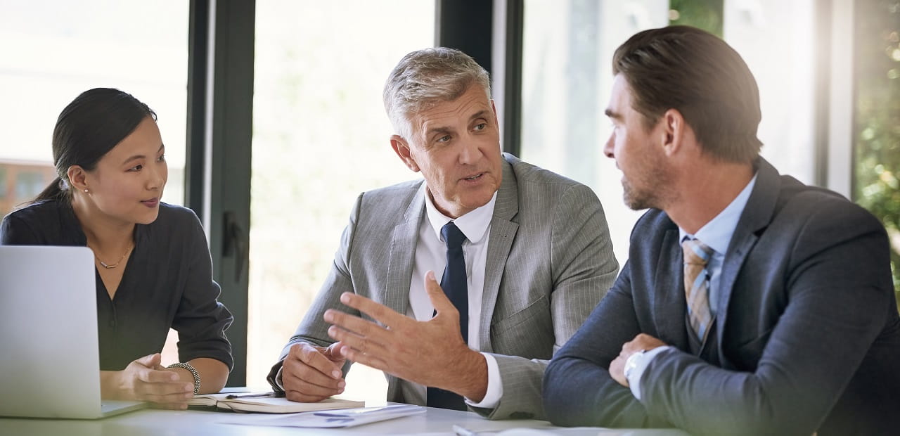 Three business professionals seated together and engaged in conversation